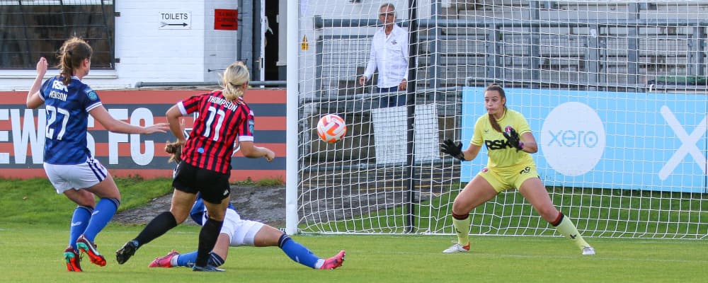 Lewes FC player shoots for goal under pressure from opposing team